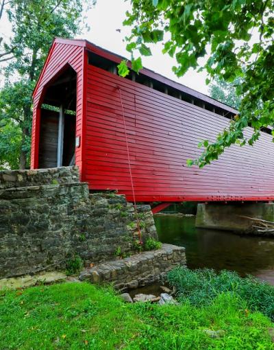 The bright red Roddy Road Covered Bridge spanning a creek near Thurmont, Maryland, USA